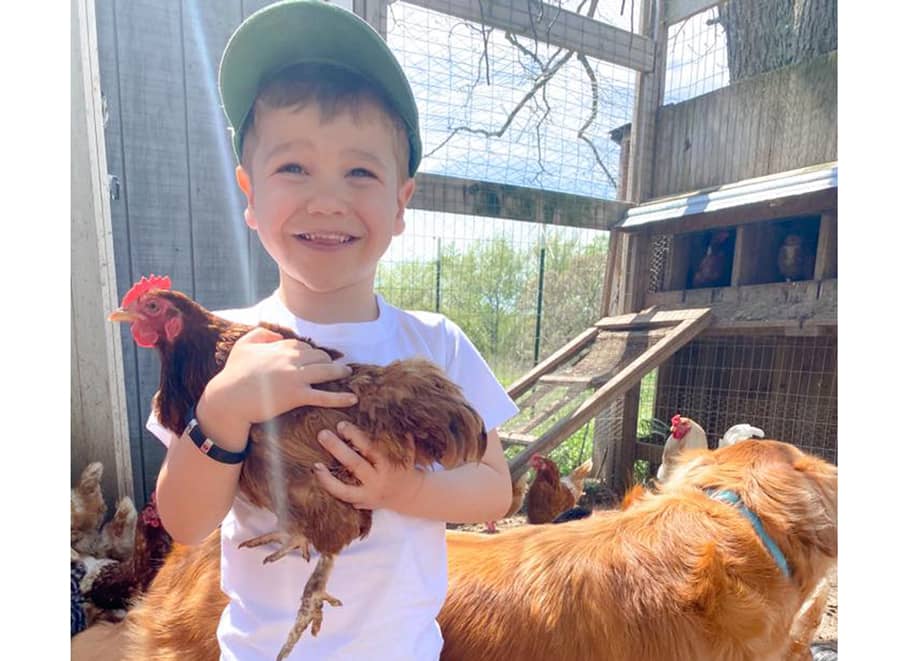 Starlight Kid Finn, happy on a farm holding a chicken